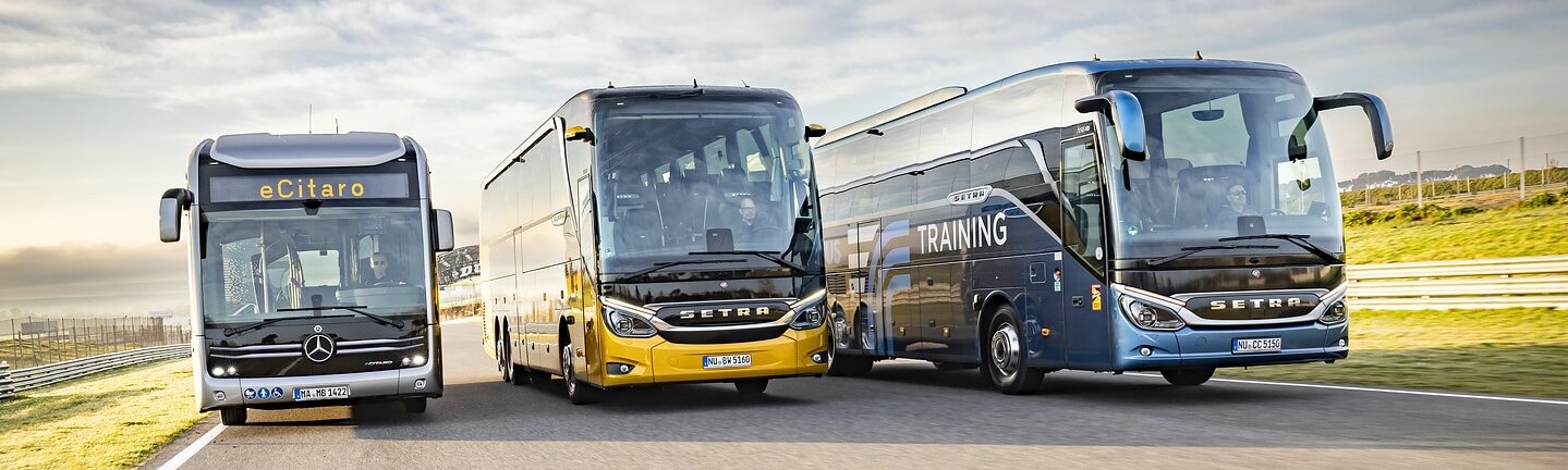 Front view of a Mercedes-Benz eCitaro city bus and two Setra coaches next to each other on a road.