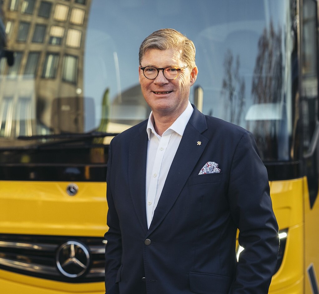 Till Oberwörder, CEO of Daimler Buses, in front of a yellow Mercedes-Benz brand coach.