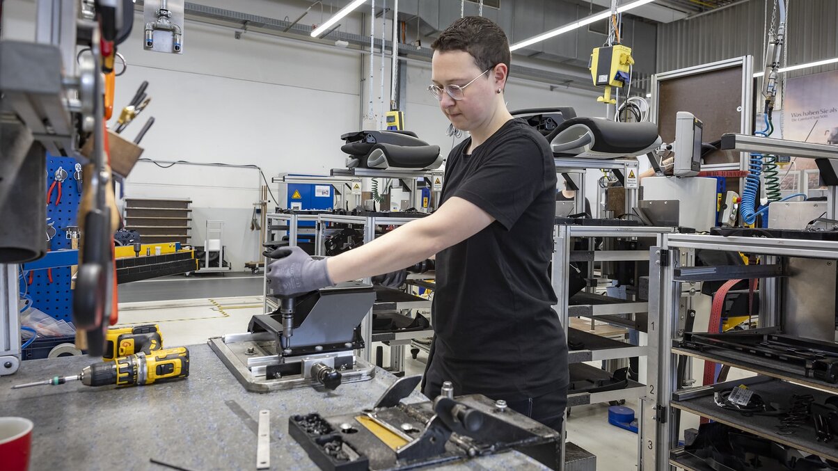 An employee assembles components at a production workstation at Daimler Buses.