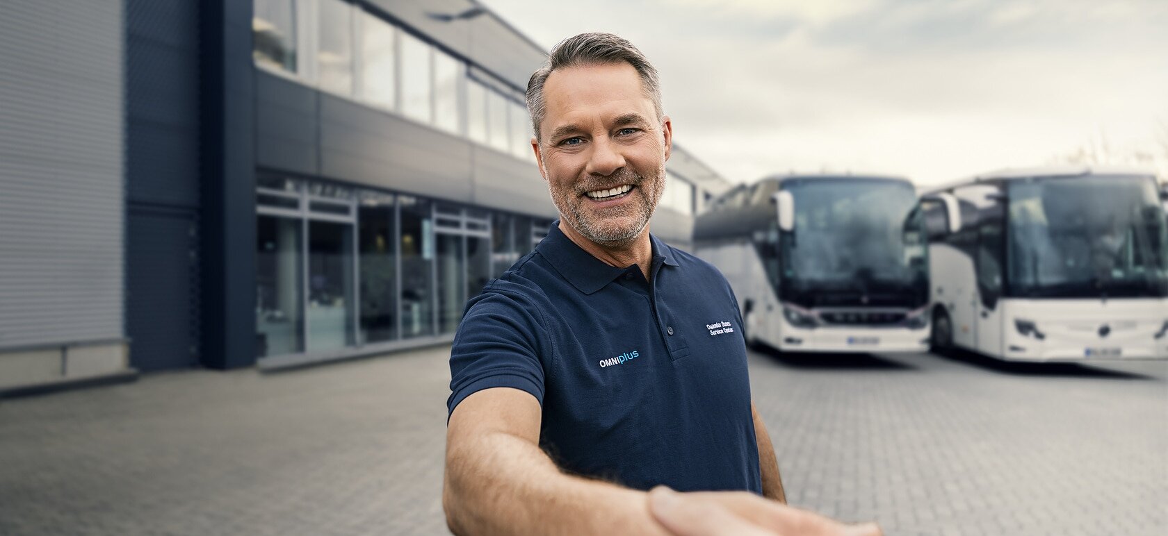 [Translate to Deutschland-en:] Employee of OMNIplus in front of coaches at a service location.
