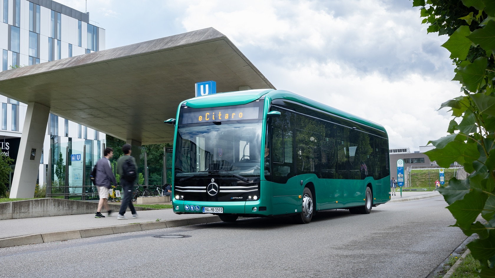 A Mercedes-Benz eCitaro electric bus at a bus stop in an urban environment.