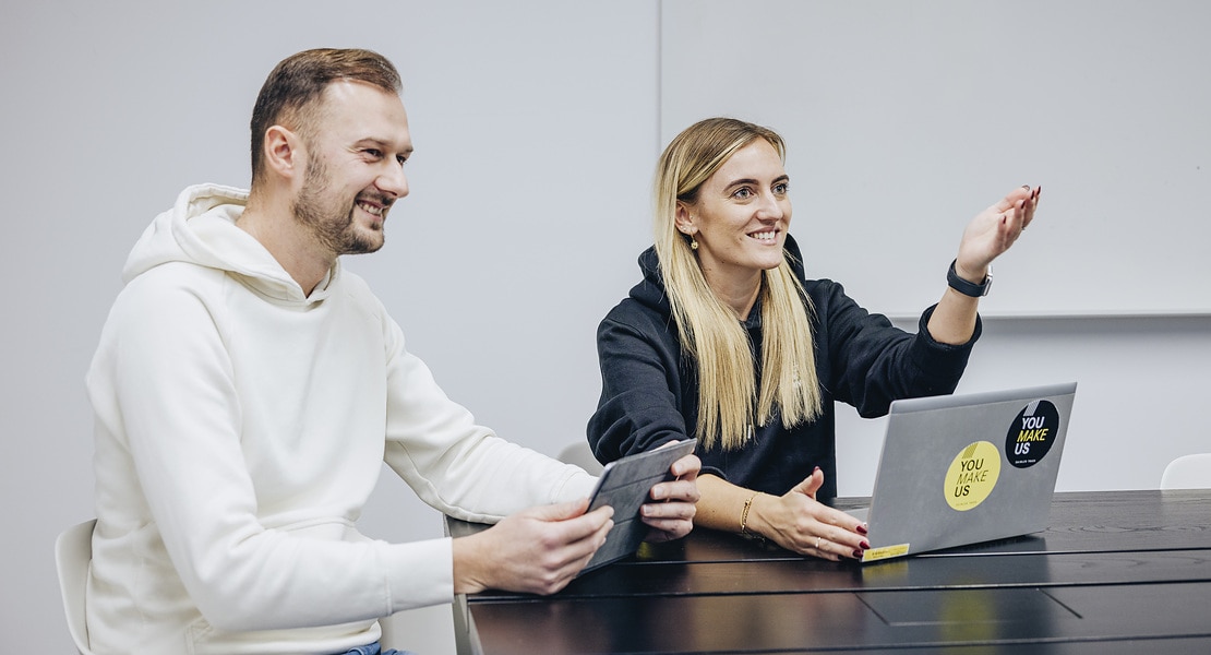 An employee and an employee are sitting at a conference table at Daimler Buses with laptops.